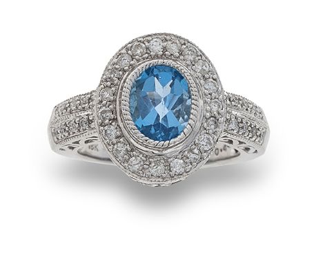 A diamond and blue topaz ring, composed of an oval mixed-cut blue topaz to a round brilliant-cut diamond surround within an 1