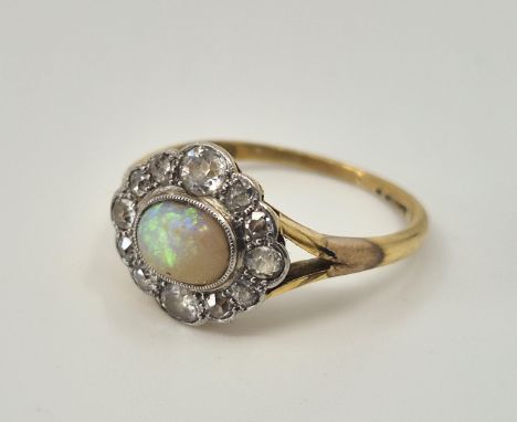 A precious yellow metal, opal and diamond ring, set oval cabochon opal (abraded) bordered by varouis cut diamonds, Size Uk M 