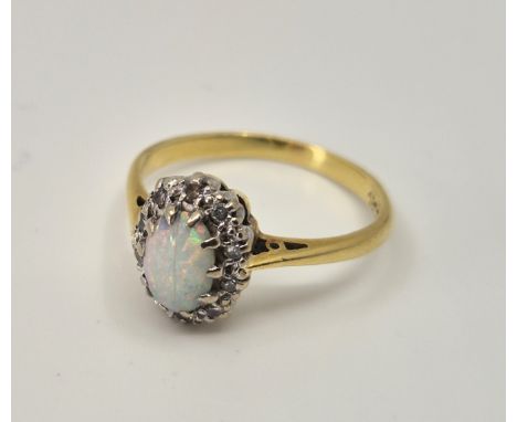 An 18ct. gold and platinum opal and diamond ring, set oval cabochon opal to centre (fracture and chip) bordered by eight-cut 