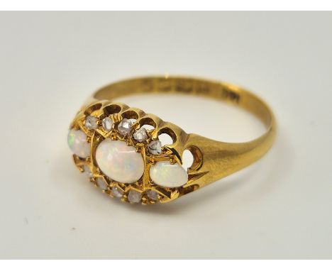 An 18ct. gold, opal and diamond ring, set three graduated oval cabochon opals with diamnd chips to sides, size UK M. (gross w