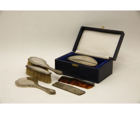 A child's silver backed hand mirror, together with matching brushes and comb, together with a cased gent's brush and comb set