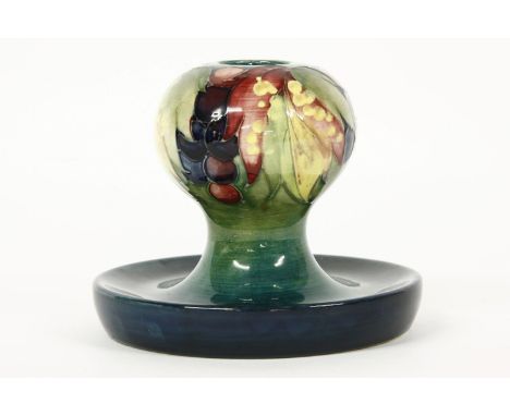 A Moorcroft candlestick, berries and leaves pattern, with dished base. 11cm high.