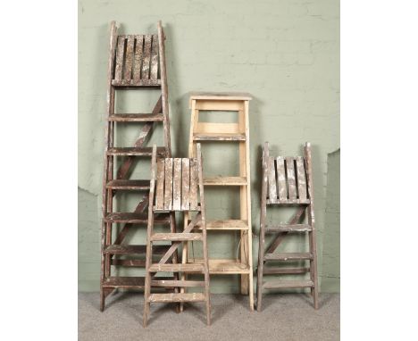 Four sets of vintage wooden stepladders.  