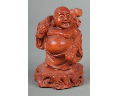A hand carved hardwood netsuke of a travelling Buddha  