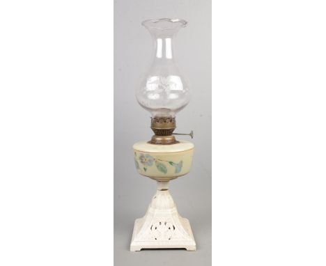 A oil lamp with cast iron painted base and glass shade.  