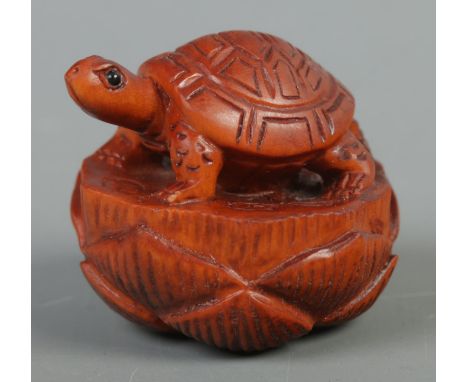 A hand carved hardwood netsuke of a turtle on lotus, signed to base.  