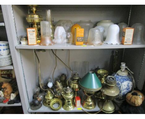 A quantity of brass oil l amps and others with various glass shades and smoke funnels, along with boxed accessories, a Delft 