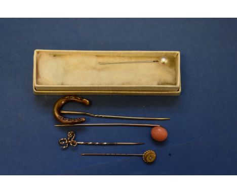 Four unmarked tie pins, to include a ruby set horseshoe; and a pearl hat-pin.