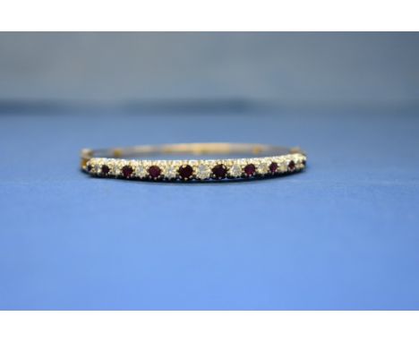 A 18ct gold diamond and garnet set hinged bangle.  Condition Report: Total weight 14g.