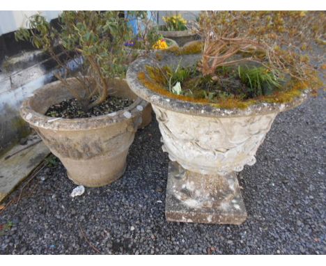 A reconstituted stone circular planter with pedestal base decorated with grapes and vines together with another similar decor