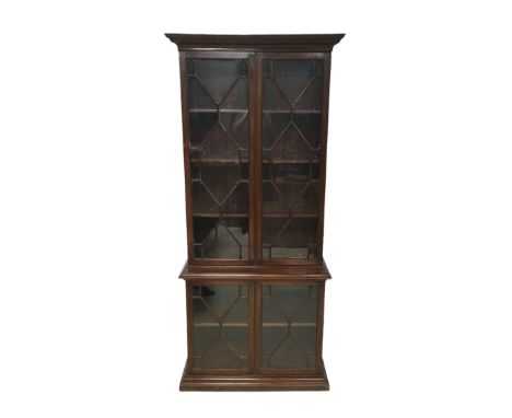 An early 20th century mahogany bookcase, the top section with three shelves, the base section with a single shelf, both secti