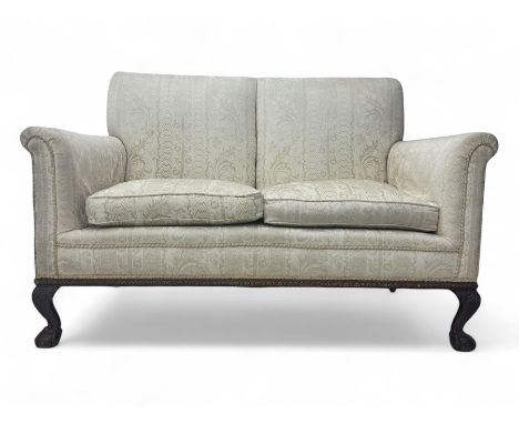 Early 20th century mahogany framed two-seat sofa, upholstered in pale fabric decorated with scrolling foliage, on acanthus ca