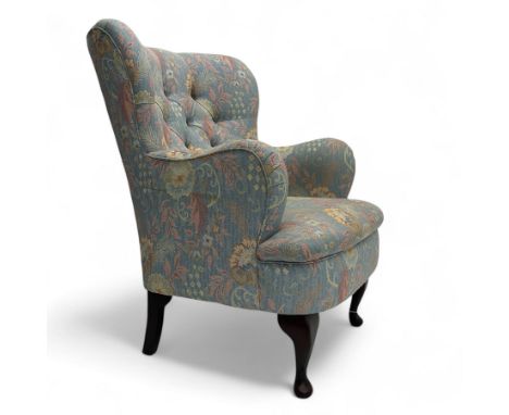 Mid-20th century wingback armchair, upholstered in soft blue floral patterned fabric with button-tufted backrest and curved a