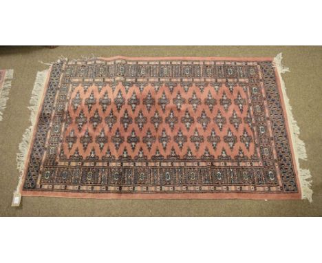 Three machine-made wool rugs of matching design with gul-decorated pink ground, largest 97cm x 155cm, the runner 64cm x 178cm