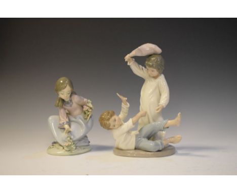 Lladro porcelain figure of a crouching girl, together with a Nao figure group of two children pillow fighting, the latter 23c