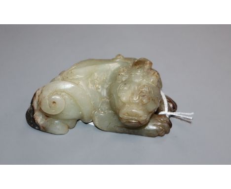 A Chinese pale grey and black jade recumbent lion-dog