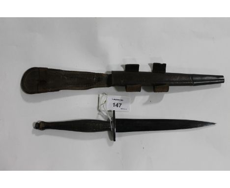 A COMMANDO DAGGER. A W W 11 issue Commando's dagger, complete with its leather sheath. The flat crossguard is marked with a '