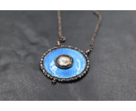 An early 20th Century silver and enamel pendant of circular form by Charles Horner having central pearl panel within blue ena