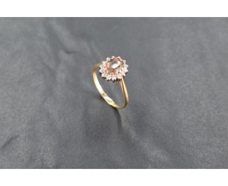 An 18ct gold andalusite and diamond cluster ring, the central raised oval-cut stone within a border of small diamond brillian