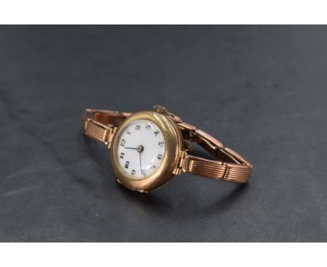 A lady's vintage 9ct rose gold wrist watch having Arabic numeral dial with gilt dots to white enamel face in a plain gold cas