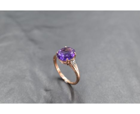 An oval heat treated amethyst ring having diamond chips to open shoulders on a 9ct rose gold loop, size R &amp; approx 2.8g