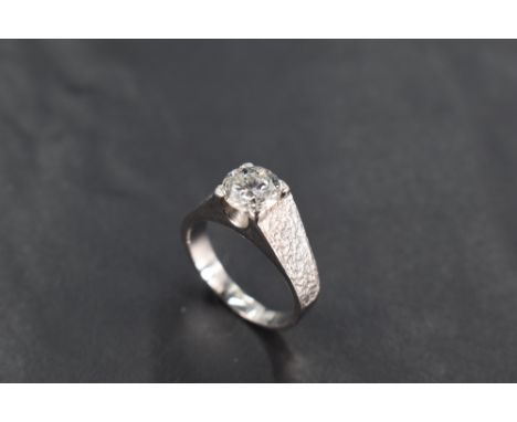 A 1970's diamond solitaire ring, approx 1.5ct in a four claw mount with brushed raised shoulders on an 18ct white gold loop, 