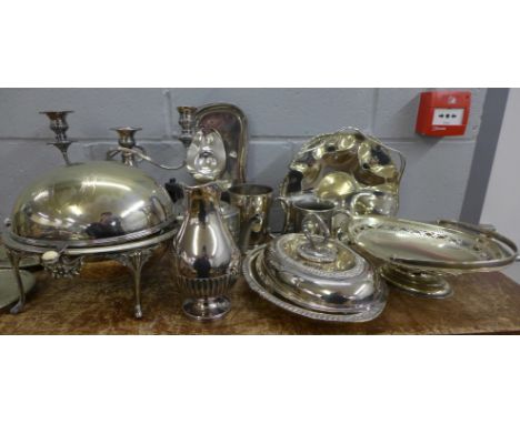 A collection of plated ware including a domed serving dish, tureen, dishes, tankards and a three branch Whitby plate candelab
