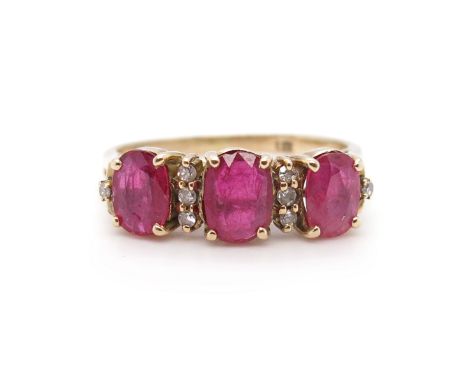 A ruby and diamond three-stone ring, set with three graduated oval-shaped rubies, with round brilliant-cut diamond pointers i