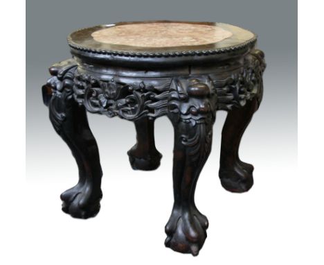 An early 20th Century Chinese hardwood and marble topped stand with carved scroll and foliage decoration, each legs having ba