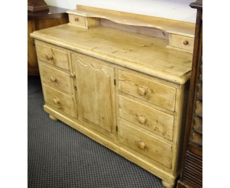 A pine dresser base with two sets of three drawers around central cupboard with low shelf to rear, together with a wall mount