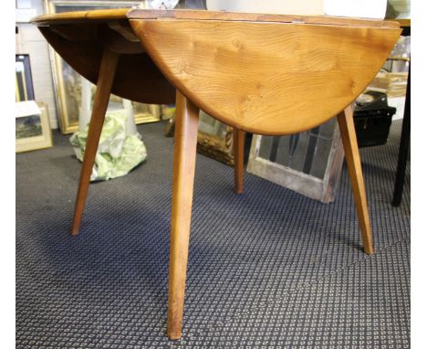 An Ercol light elm dining table with drop leaf sides.