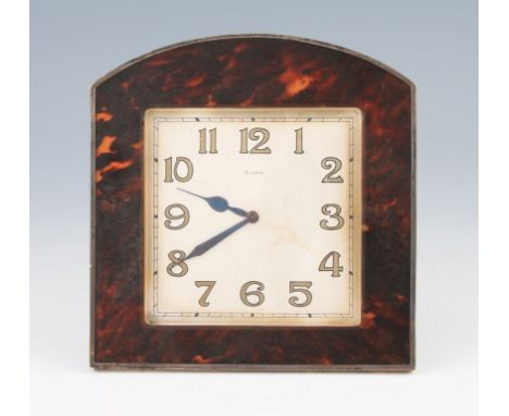 An Art Deco tortoiseshell surround clock, the square dial having hourly Arabic numeral markers with minute track border, with