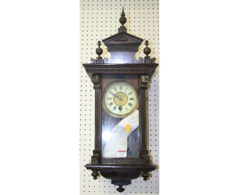 A small early 20th century walnut drop trunk wall clock with pendulum