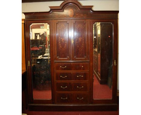 An Edwardian mahogany, flame mahogany and floral satinwood inlaid triple wardrobe, the arched cornice over twin panelled cupb