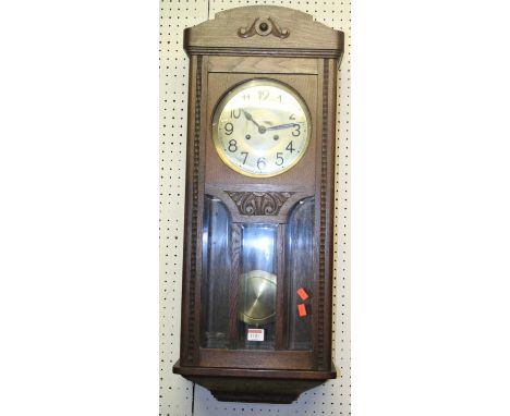 A 1930s oak drop trunk wall clock with pendulum, height 80cm