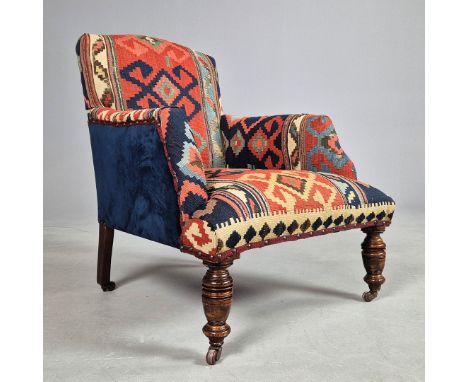 VICTORIAN ARMCHAIR IN KILIM UPHOLSTERY. Raised on turned front supports and ceramic castors86cm H x 66cm W x 75cm D.