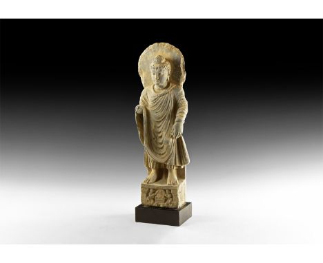 2nd-4th century AD. A carved schist statue of Buddha standing facing in loose garment, right arm extended forward, left hand 