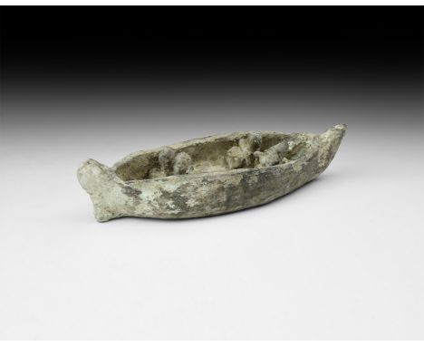7th-6th century BC. A greyware ceramic model boat with scooped prow and stern rudder, four model crew members seated with pil