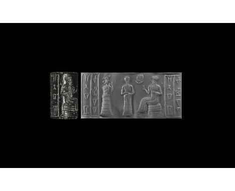 19th century BC. A black limestone cylinder seal with suppliant goddess standing in long dress with raised hands behind a wor