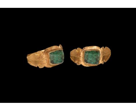 3rd century AD. A gold finger ring comprising a narrow hoop with angled lyre-shaped shoulders, square cell with inset emerald