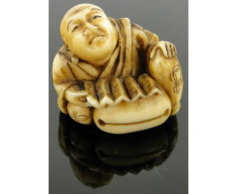 A late 19th century carved ivory netsuke
depicting a man with a bell, signed, height 1.2".