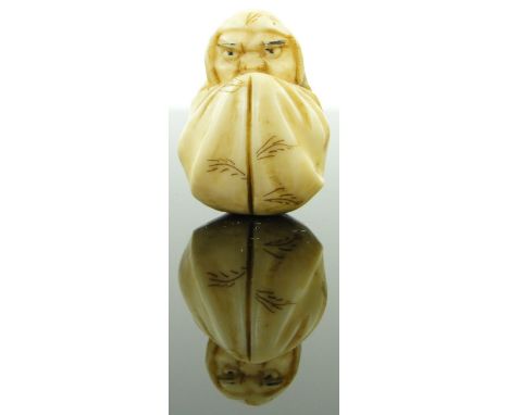 A late 19th century ivory netsuke
depicting a man hiding in a sheet, 1.1".