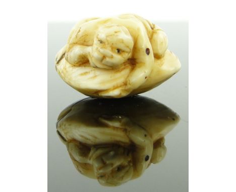 A late 19th century ivory netsuke
depicting a man crouched on a shell, length 1.2".