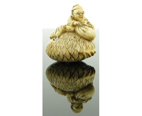 A late 19th century netsuke
depicting a man seated on a large fish, height 1".