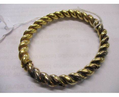 A yellow metal bangle with rubies and diamond stones