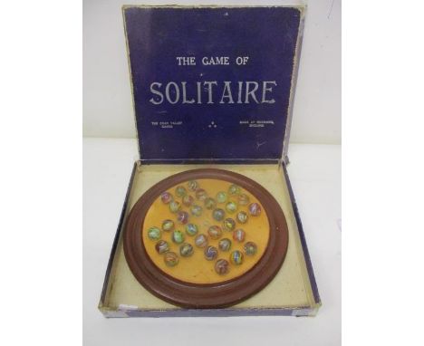 A Chad Valley solitaire game with thirty two marbles, decorated with swirls, and a brown painted plywood board, in its origin