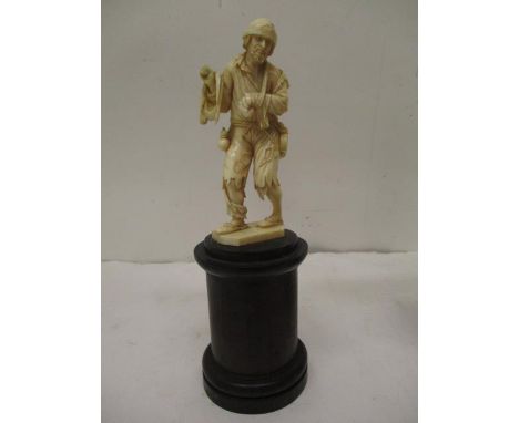 A late 19th century Dieppe carved ivory figure of man wearing tattered clothes, with his arm in a sling, a bag over his shoul