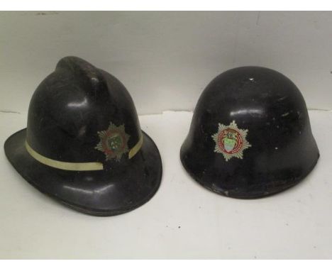 Two vintage fireman's helmets, one fibreglass with a Cumbria Fire Service transfer badge and the other a black, cork core hel