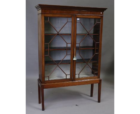 A late 19th century mahogany bookcase on later stand, the dentil pediment above astral glazed doors, the stand with square ta