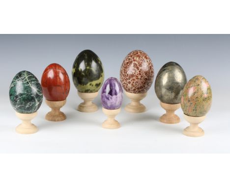 A group of seven large polished mineral egg specimens, largest 14cm, each with a turned wooden stand.Buyer’s Premium 29.4% (i